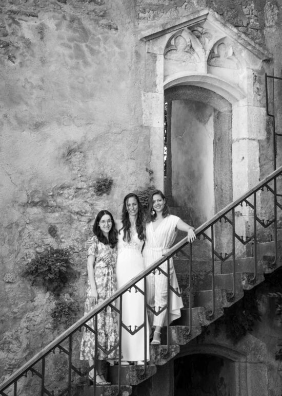 Braut steht mit zwei Freundinnen auf der Treppe