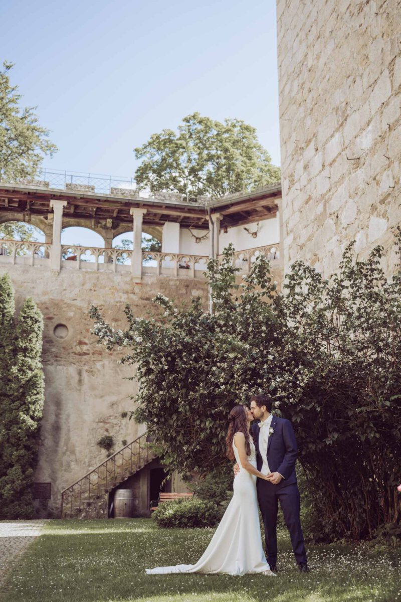 Hochzeitspaar küsst sich im Innenhof von Schloss Egg