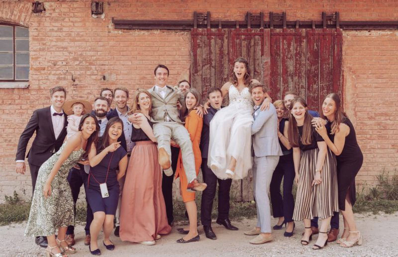 Hochzeitsgäste tragen das Brautpaar auf Händen