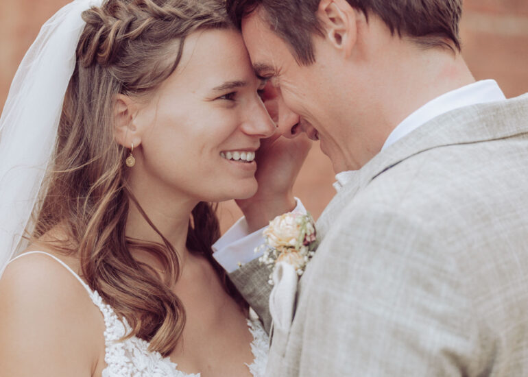 Hochzeitspaar lächelt und schaut sich verliebt in die Augen