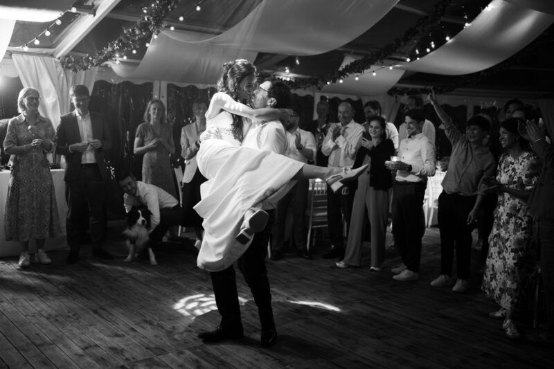 Bräutigam hebt die Braut beim Hochzeitstanz in die Luft