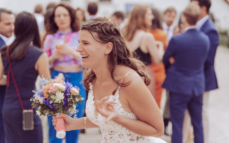 Braut läuft lachend durchs Bild und hält ihren Brautstrauß in der Hand