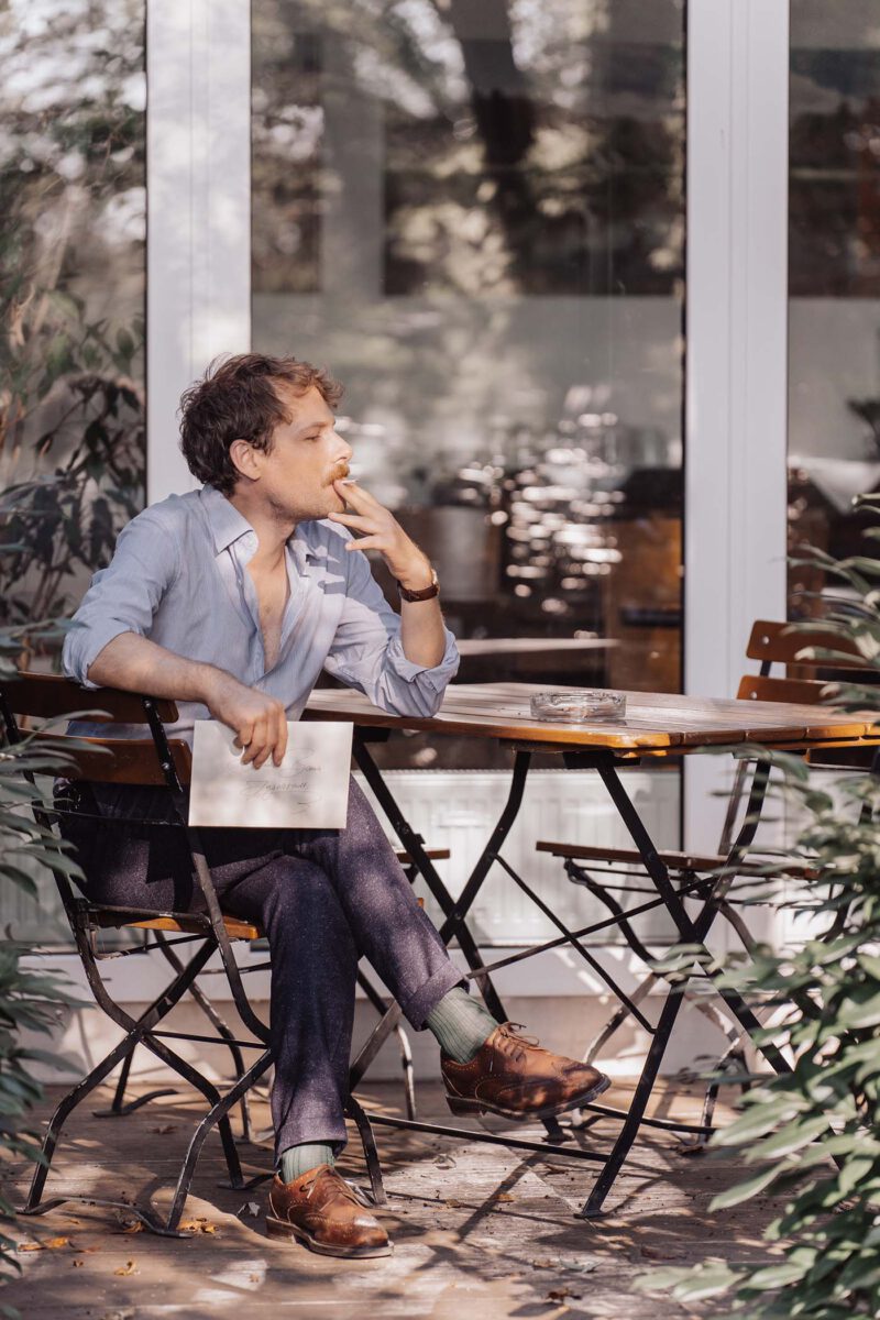 Hochzeitsgast sitzt auf Stuhl und raucht eine Zigarette