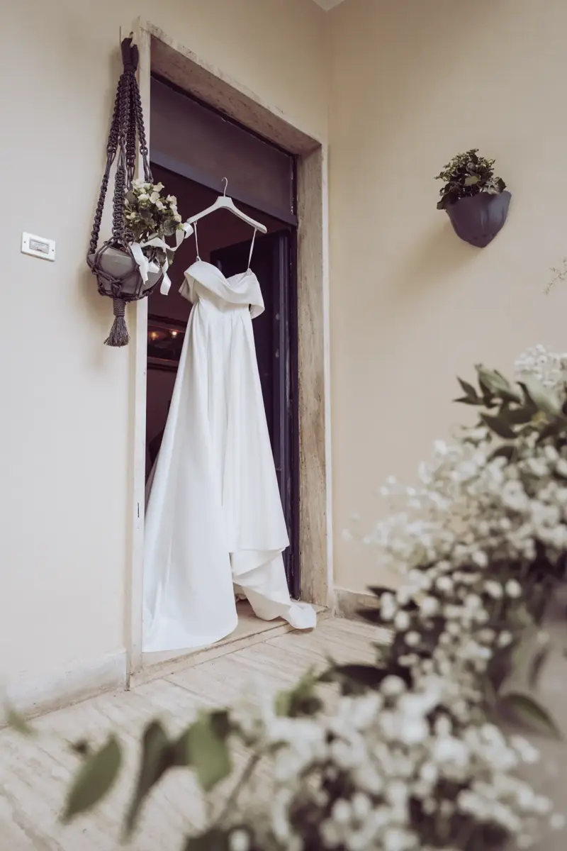 Brautkleid hängt an der Haustür, im Vordergrund sind Blumen
