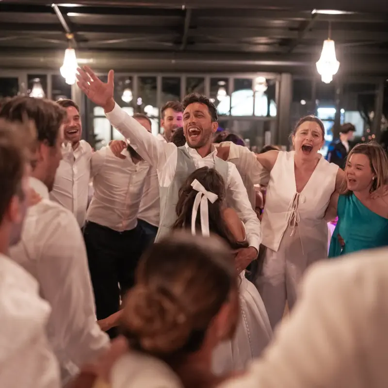 Bräutigam feiert ausgelassen auf der Tanzfläche mit anderen Gästen um sich