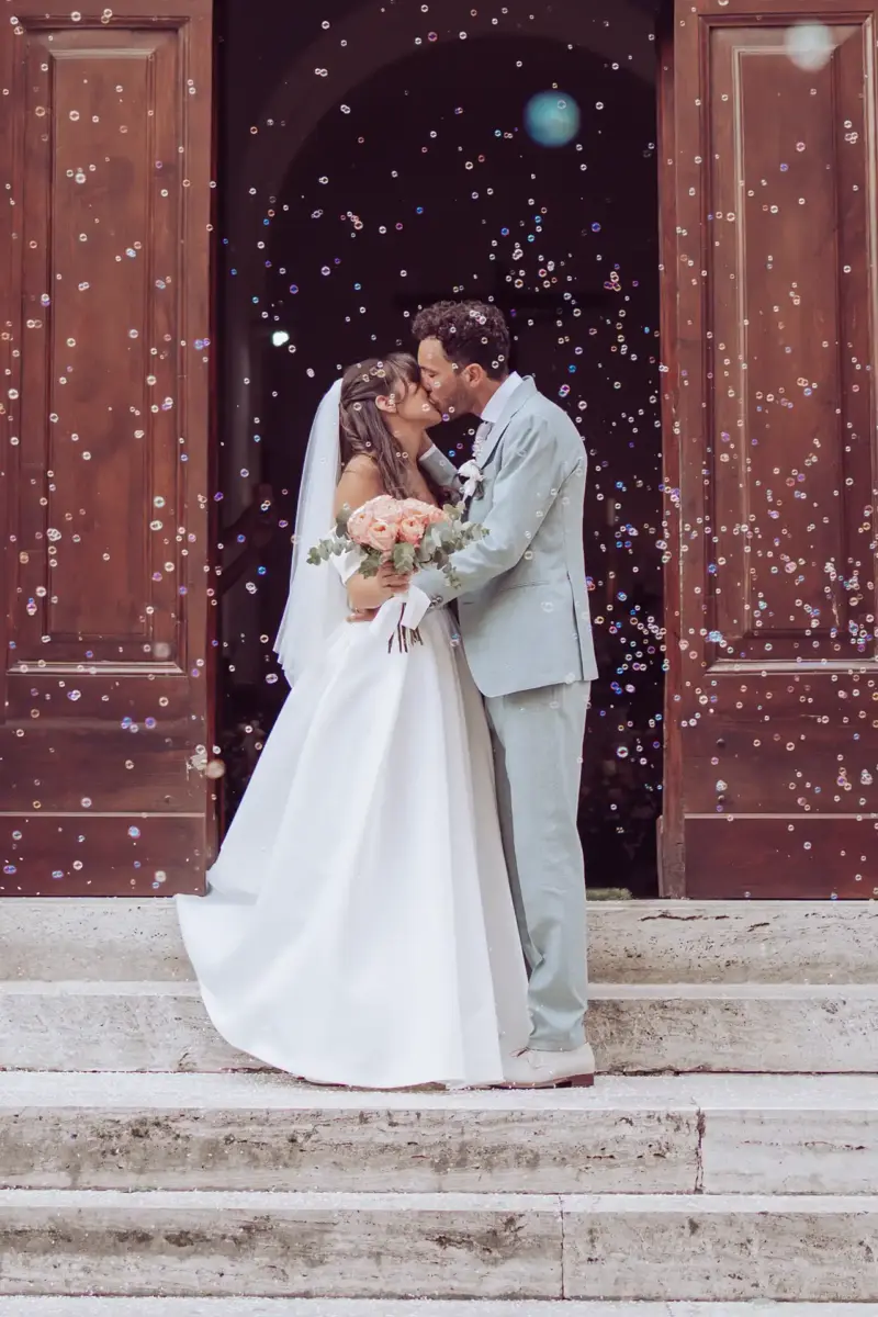 Brautpaar küsst sich auf Treppe und ist von Seifenblasen umgeben