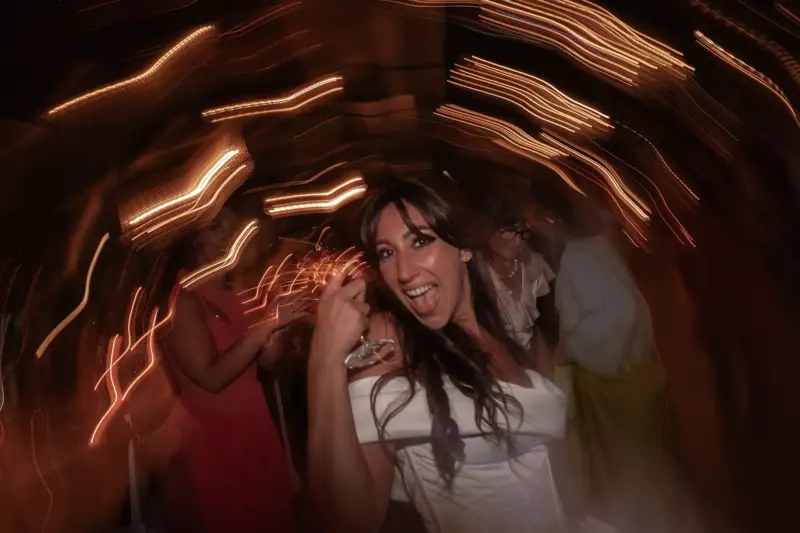 Braut schaut lauf der Tanfläche mit Sektglas in der hand achend in die Kamera