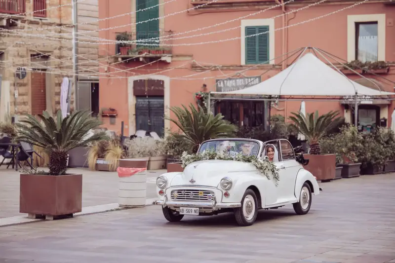 Braut fährt im Oldtimer Cabrio auf dem Rücksitz zur Kirche