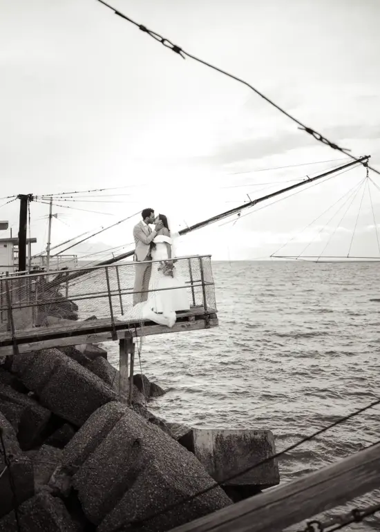 Brautpaar steht auf Steg am Hafen und küsst sich, Schwarz-Weiß