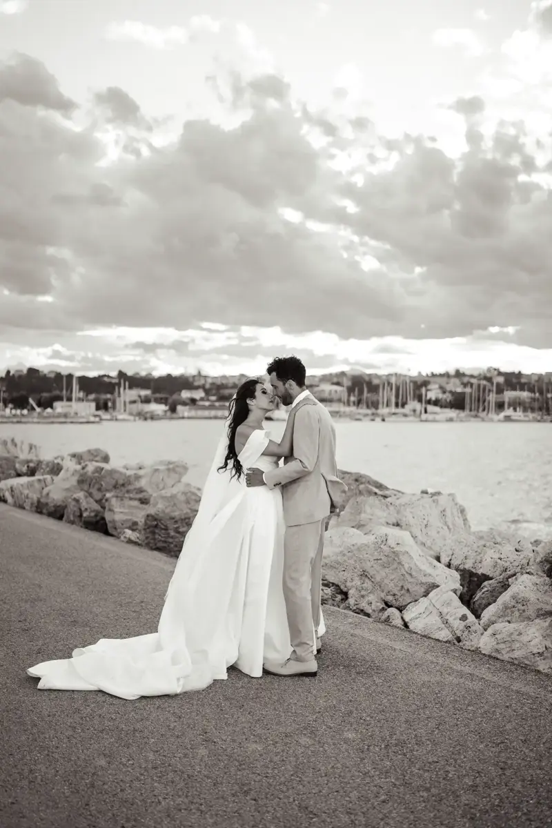 Brautpaar umarmt sich am Hafen und küsst sich gleich, Schwarz-Weiß