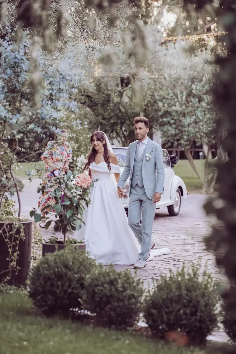 Braut und Bräutigam halten Händchen und sind von Pflanzen umgeben