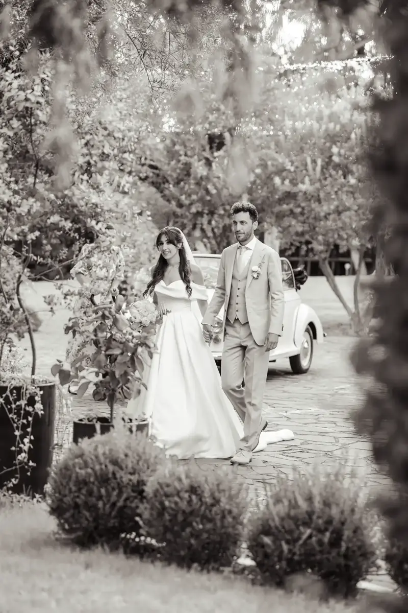 Braut und Bräutigam halten Händchen und sind von Pflanzen umgeben, Schwarz-Weiß