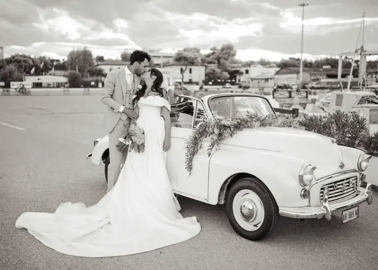 Brautpaar steht vor Oldtimer Cabrio am Hafen und küsst sich, Schwarz-Weiß