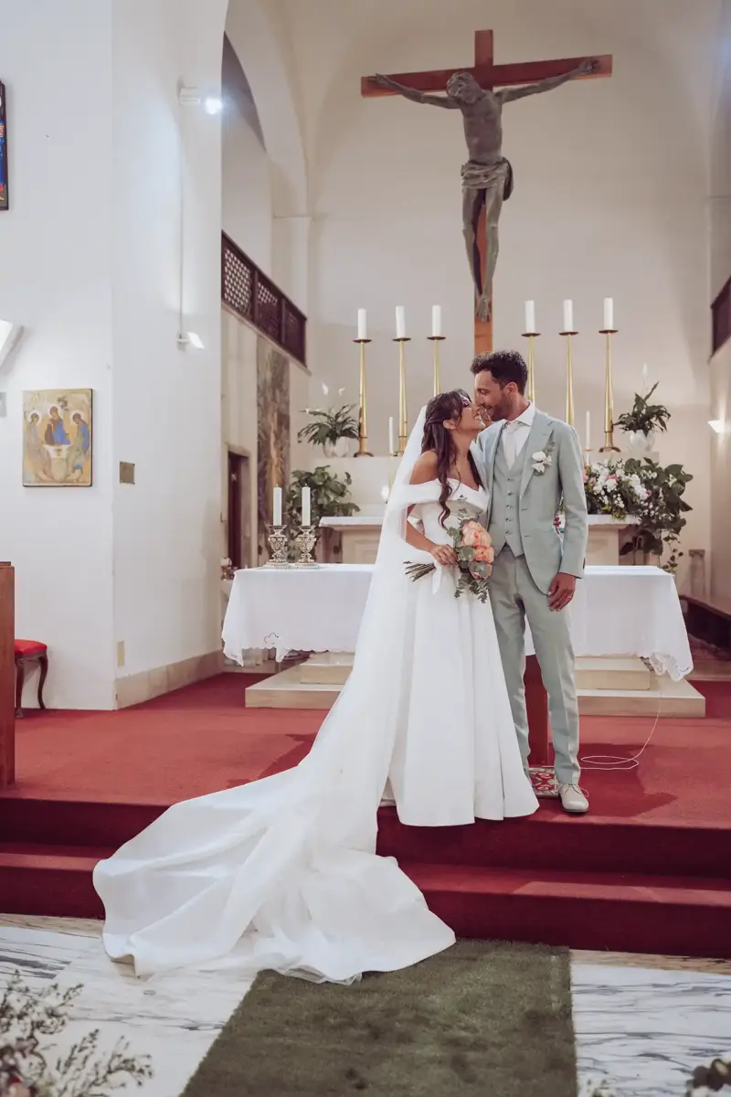 Brautpaar steht vor dem Altar und Kreuz Jesu in der Kirche und schaut sich an
