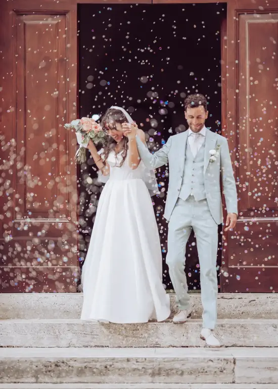 Brautpaar kommt aus Kirche und ist umgeben von Seifenblasen