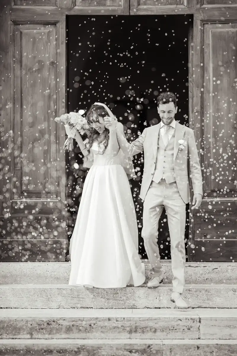 Brautpaar kommt aus Kirche und ist umgeben von Seifenblasen, Schwarz-Weiß