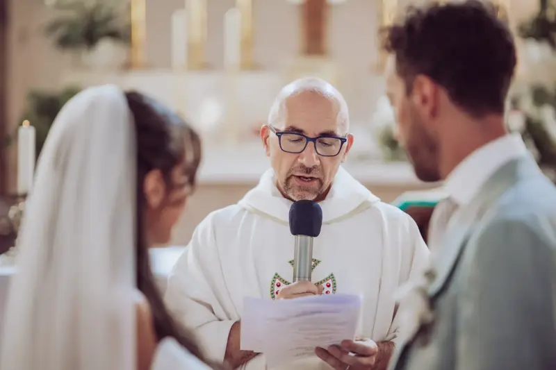 Pfarrer liest Braut und Bräutigam mit Mikrofon in der Hand etwas vor