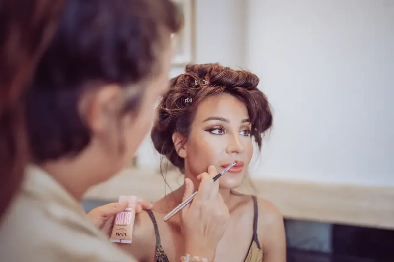 Schwester der Braut wird von Stylistin im Gesicht geschminkt