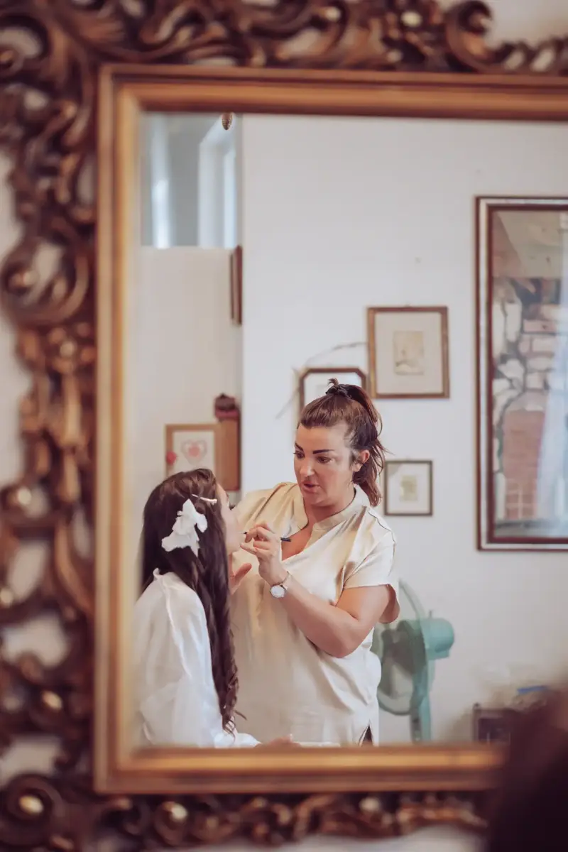 Braut mit Stylistin im Spiegel