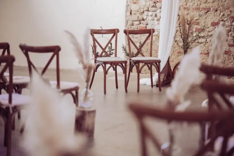 Die zwei Stühle von Braut und Bräutigam stehen neben dem Traubogen