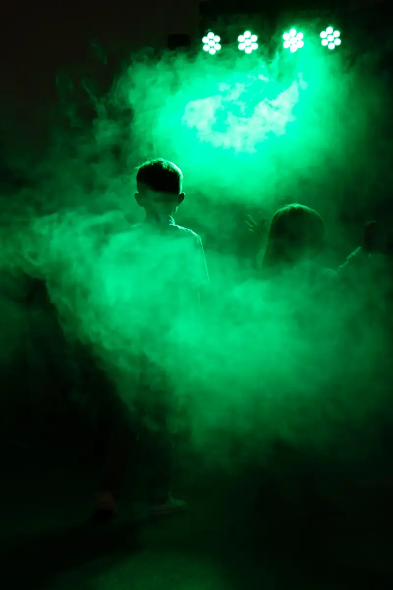 Zwei Kinder stehen im Nebel auf der Tanzfläche und werden grün angestrahlt