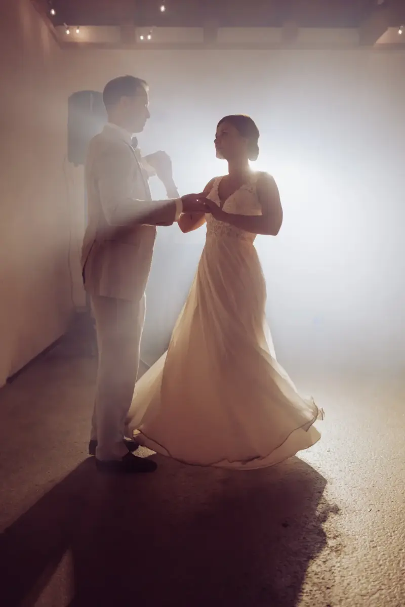 Das Brautpaar steht auf der Tanzfläche im grellen Licht und tanzt