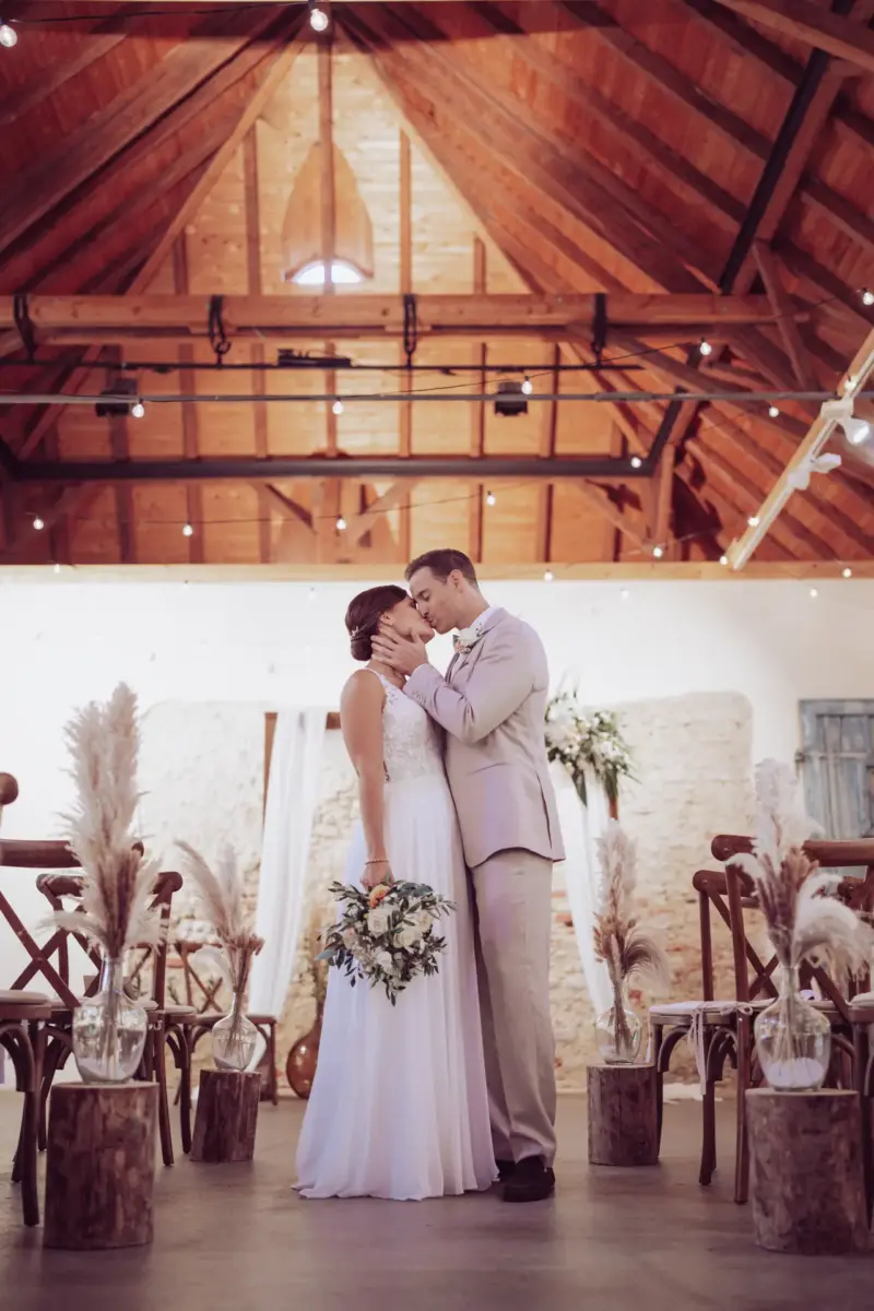 Brautpaar küsst sich vor dem Traubogen in der Remise Schloß Fußberg