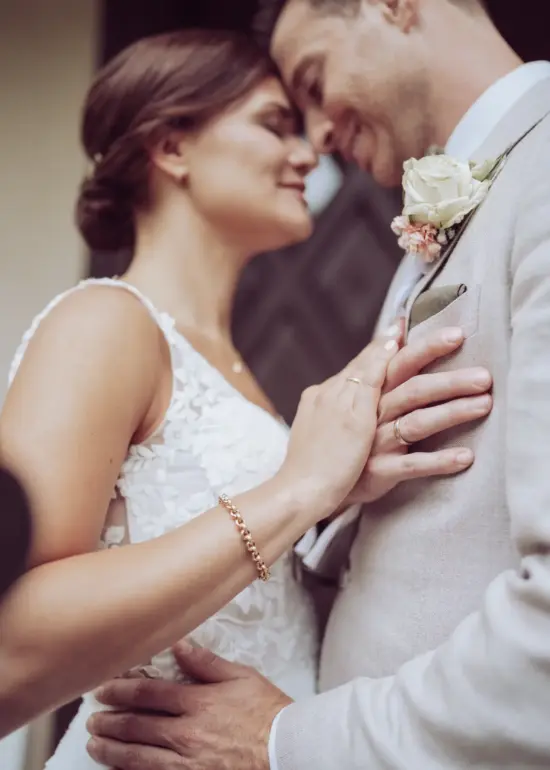 Brautpaar steht eng an eng, die Eheringe sind zu sehen