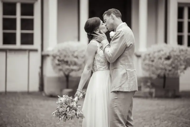 Brautpaar küsst sich vor der Remise Schloß Fußberg