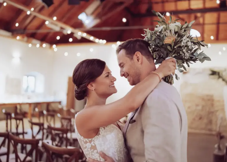 Brautpaar lacht sich an, Braut hält den Brautstrauß hinter seinem Kopf