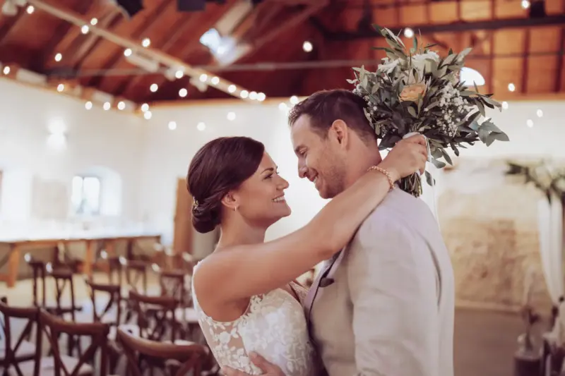 Brautpaar lacht sich an, Braut hält den Brautstrauß hinter seinem Kopf