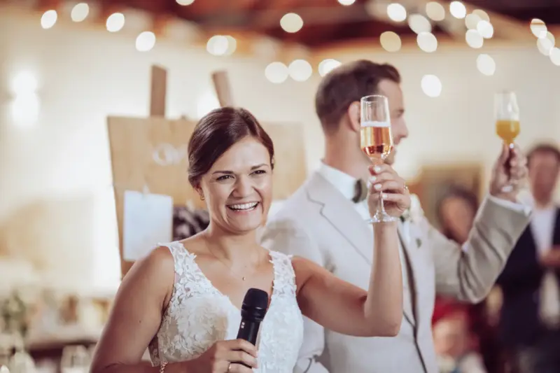 Braut und Bräutigam prosten den Gästen zu