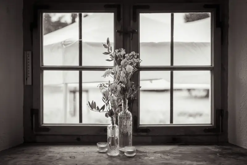 Zwei Blumenvasen sehen dekorativ vor einem Fenster der Remise Schloß Fußberg