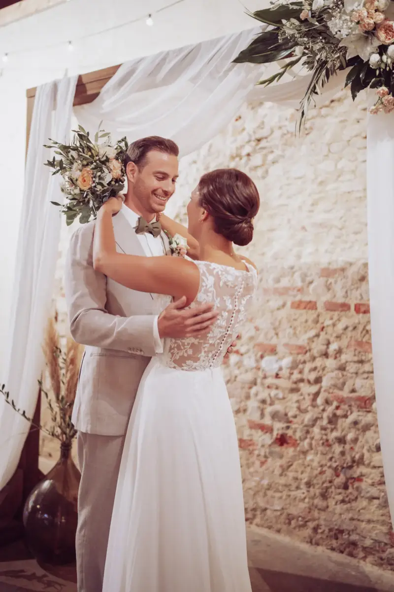 Brautpaar steht unter dem Traubogen in der Remise Schloß Fußberg und umarmt sich